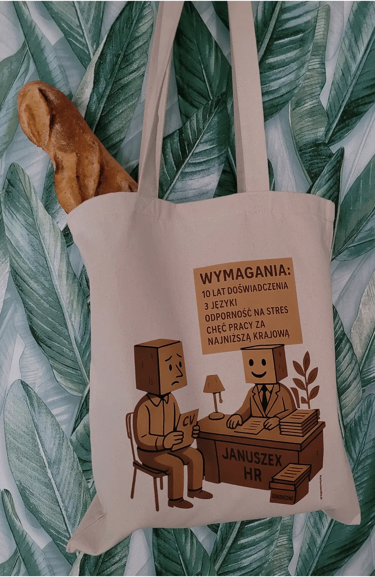 Torba bawełniana Kartonlandii z grafiką Januszex HR i napisem Wymagania: 10 lat doświadczenia, 3 języki, odporność na stres, chęć pracy za najniższą krajową